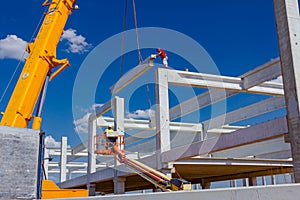 Workers are helping crane to keep balance and direction of concrete joist