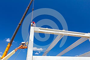 Workers are helping crane to keep balance and direction of concrete joist