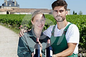 workers holding wine bottle in vineyard