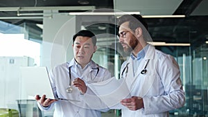 Workers of hospital with stethoscopes using laptop for solving working issues