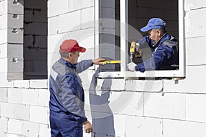 Workers install glazing in a house under construction