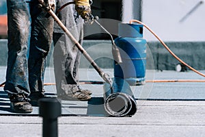 Workers installing bituminous membrane waterproofing system insulation with blowtorch photo