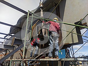 Workers are installing bracing steel beam of steel structure work at industrial factory