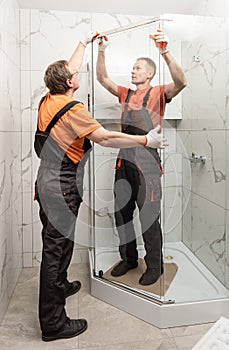 Workers are installing door of the shower enclosure