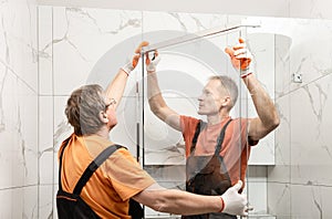 Workers are installing door of the shower enclosure