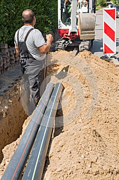 Workers installing optical fibre cables in shallow trenches.