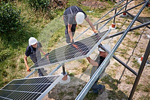 Workers installing solar panel on metal beams