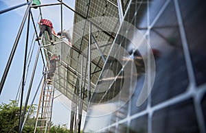 Workers installing solar panels on metal beams