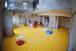 Workers installing underfloor heating system