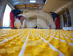 Workers installing underfloor heating system