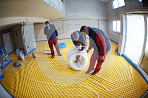 Workers installing underfloor heating system