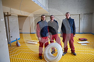 Workers installing underfloor heating system