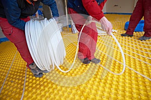 Workers installing underfloor heating system