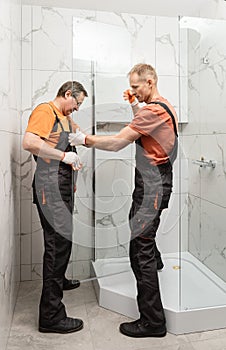 Workers are installing a wall shower enclosure