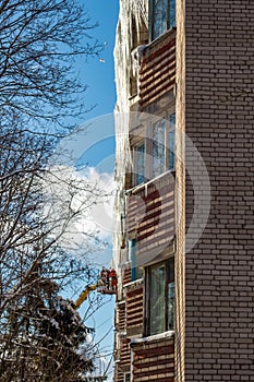 Workers knock down icicles from the roof in winter