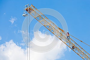 Workers on a large construction crane on blue sky
