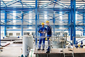 Workers in large metal workshop checking work