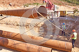 Workers are laying metal culverts under the highway under construction