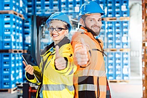 Workers in logistics distribution center showing thumbs-up