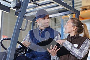 Workers in logistics warehouse at forklift checking list