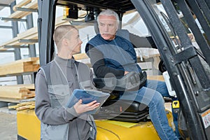 workers in logistics warehouse at forklift checking list