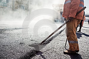 Workers making asphalt with shovels at road