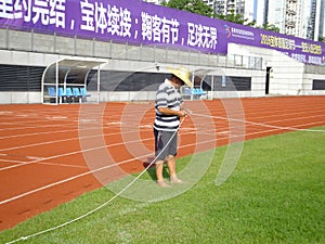 Workers measure the football field on the lawn with a roller rope