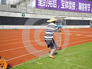 Workers measure the football field on the lawn with a roller rope