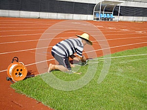 Workers measure the football field on the lawn with a roller rope