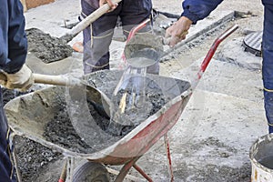 Workers mixing the cement by hand in wheelbarrow 2