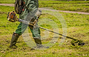 Workers mow the grass on the lawn in the city square.