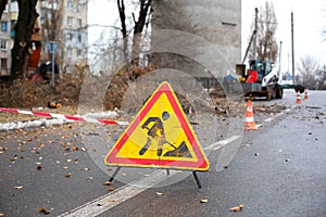 Workers in the municipal utilities cut branches from trees, blocking the street