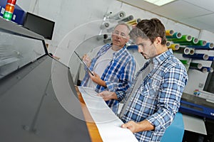 Workers on offset printing machine in print factory