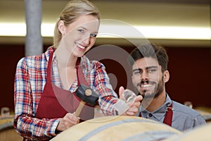 Workers posing and smiling next to barrel