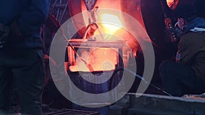 Workers poured molten metal at plant. Stock footage. Workers in form and helmets control process of pouring molten metal