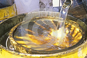 Workers pouring toxic wastes into a metal drum