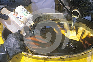 Workers pouring toxic wastes into a metal drum