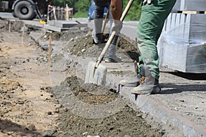 Workers prepare the surface for the installation of road curbs.