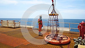 Workers are preparing the personal basket to lift by the crane to the offshore platform,