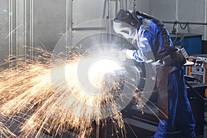 Workers in protective equipment in a foundry work on a casting with a grinding machine at the workplace