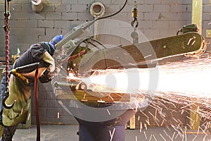 Workers in protective equipment in a foundry work on a casting with a grinding machine at the workplace photo