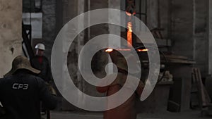 Workers in protective gear handle molten metal at steel casting foundry. Industrial team in a factory pour and mold high