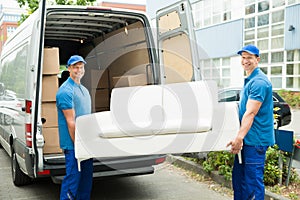 Workers Putting Furniture And Boxes In Truck