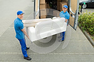 Workers Putting Furniture And Boxes In Truck