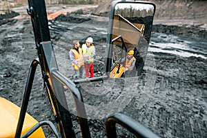 Workers in quarry seen in the mirror of a heavy-duty truck