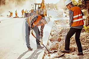 Workers in reflective vests using shovels during carriageway work