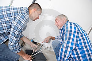 Workers repair pipes boiler in heating room