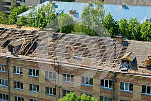 Workers repair and replace roofing on an old red brick building. Spring construction work. Repair and maintenance of city