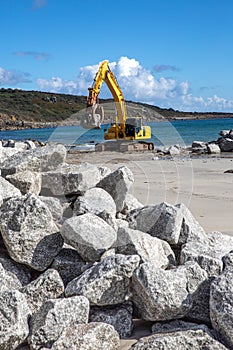Workers repairing damaged coastal wall defences on a beach