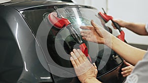 Workers replacing windscreen of car in a service station windshield replacement